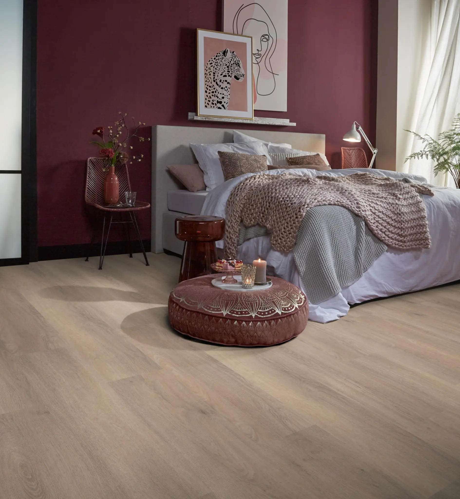 Lichte eikenlook laminaatvloer in een slaapkamer met bordeauxrode wand